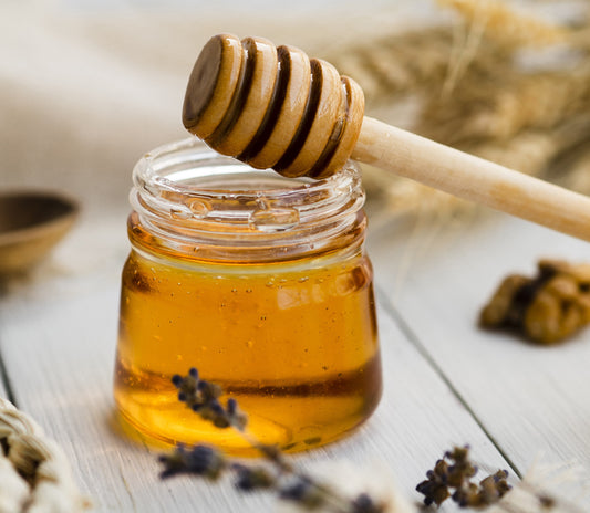 Kashmiri wildflower honey in a glass jar with a honey dripper