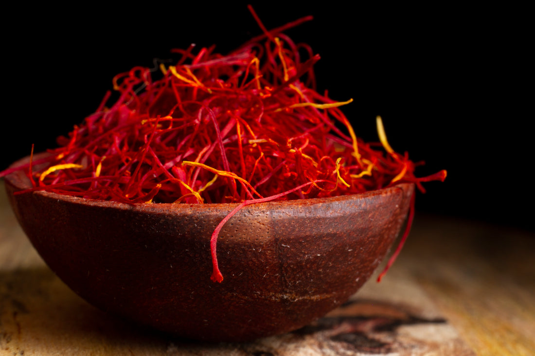 A bowl with saffron stands on a wooden surface