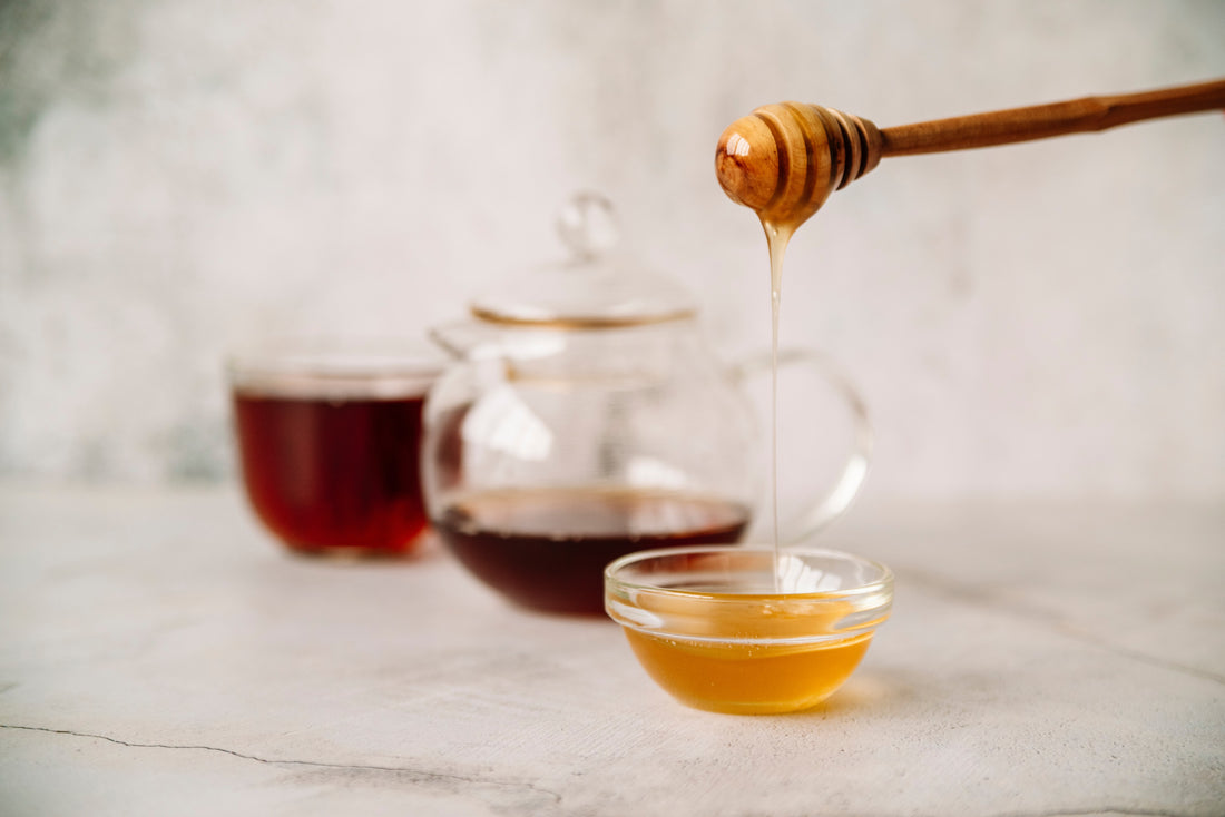 Acacia honey in a cup with a dripper